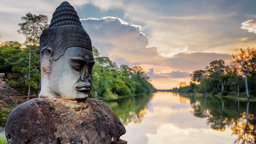 Stone Asura And Sunset Over Moat Surrounding Angkor